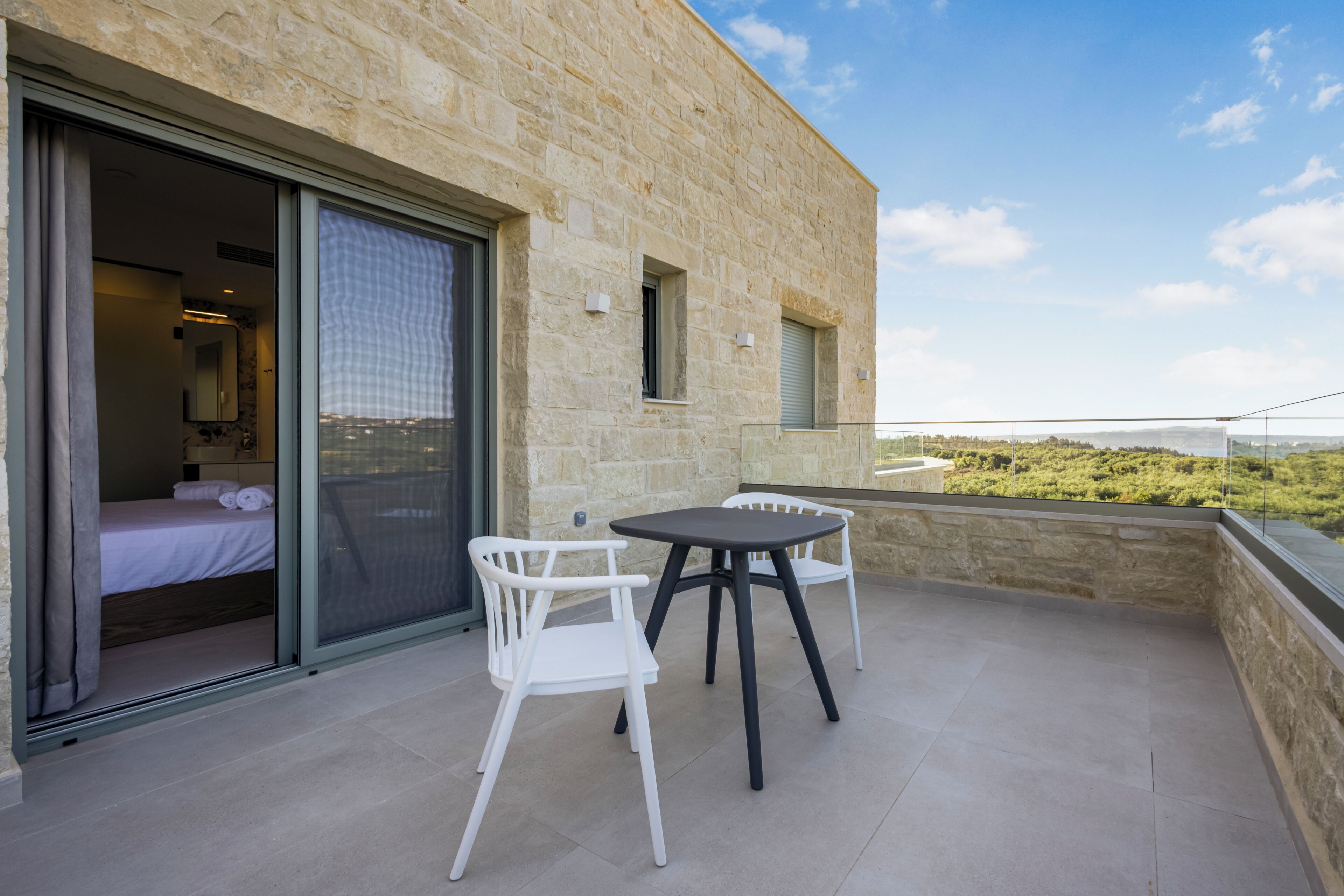 Un balcone con un letto, due sedie e un tavolo.