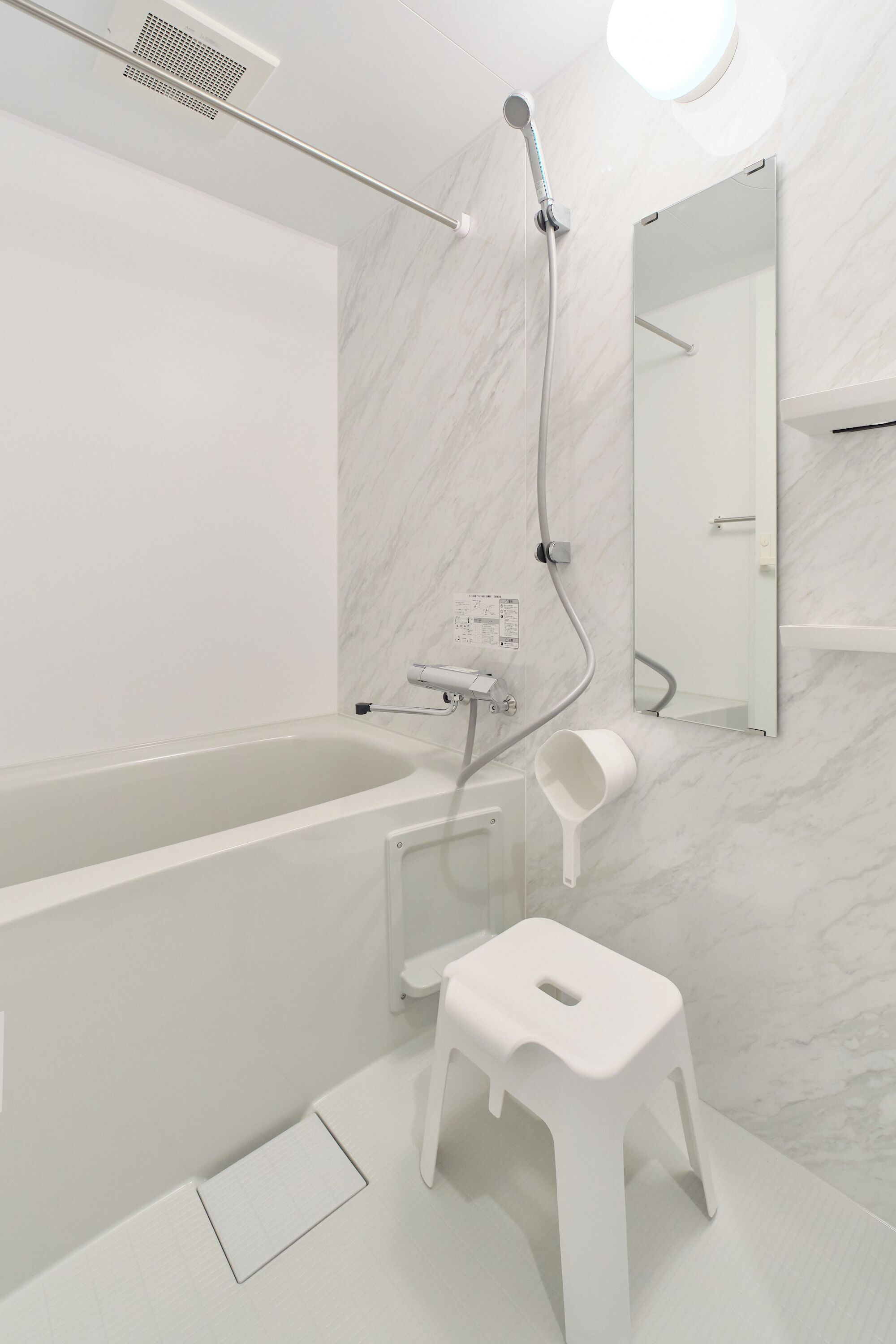 Une salle de bain moderne équipée d’une baignoire, d’une douche, de toilettes et d’un petit tabouret.