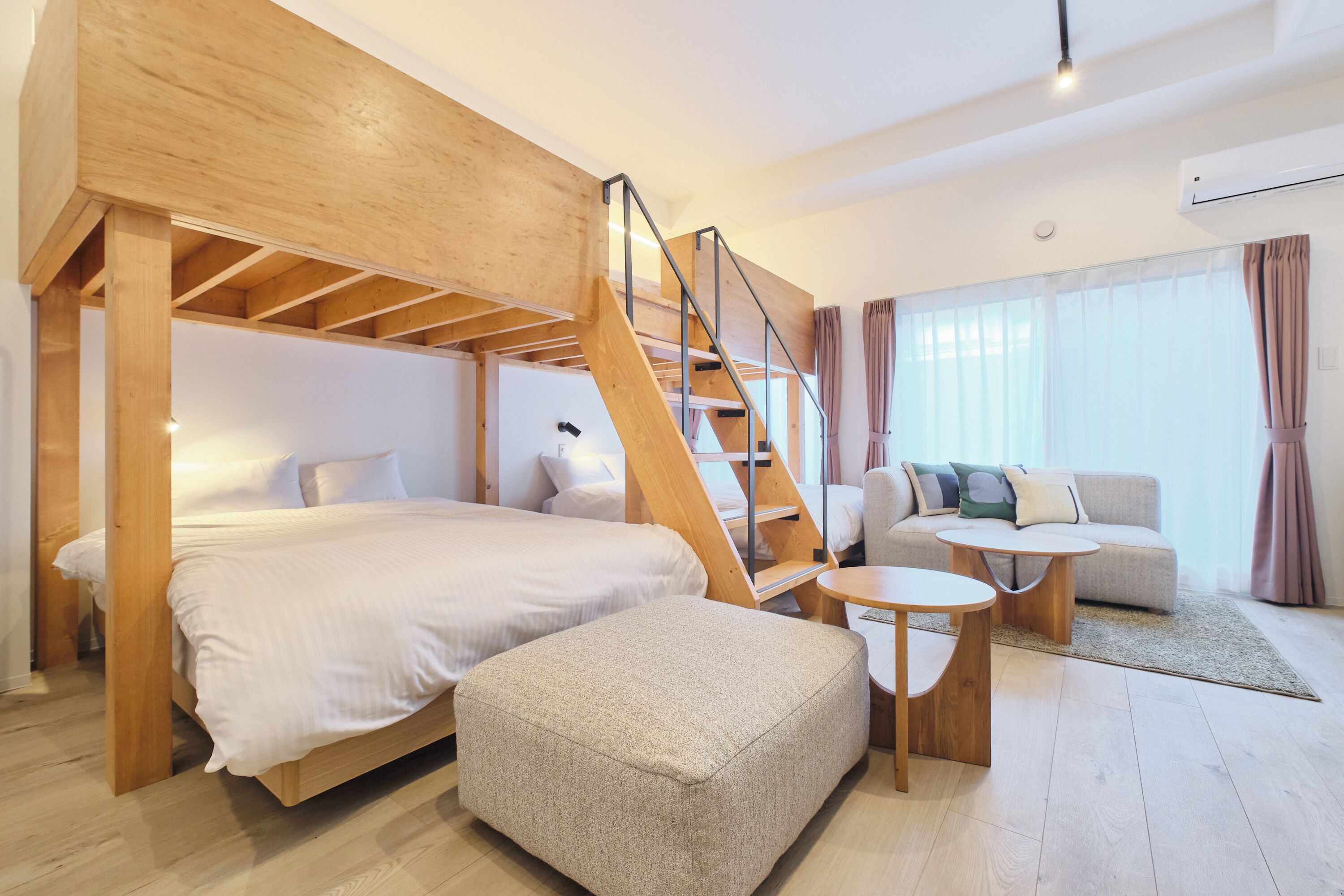 Una habitación de hotel moderna con una escalera de madera, un sofá, una mesa redonda de centro y una cama.