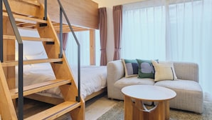 A room with a bunk bed, a sofa, and a round coffee table.