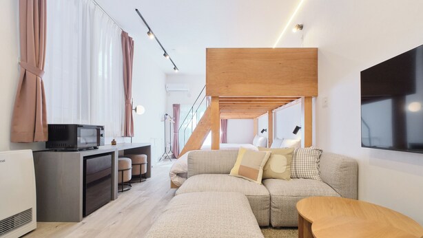 A modern living room with a sectional sofa, a flat-screen TV, a wooden coffee table, and a built-in kitchen area.