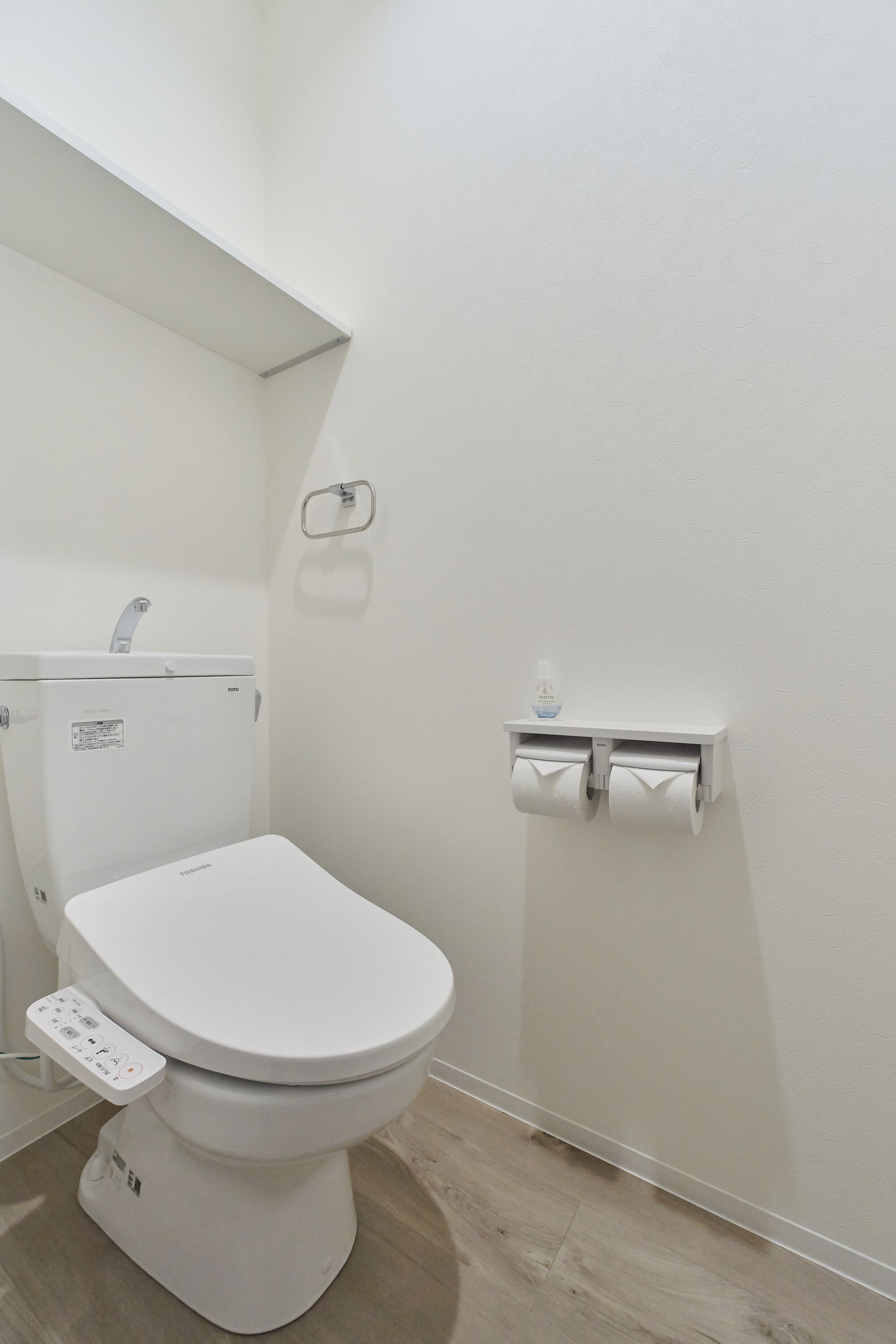 A modern bathroom with a toilet, a hand dryer, and a paper towel dispenser.