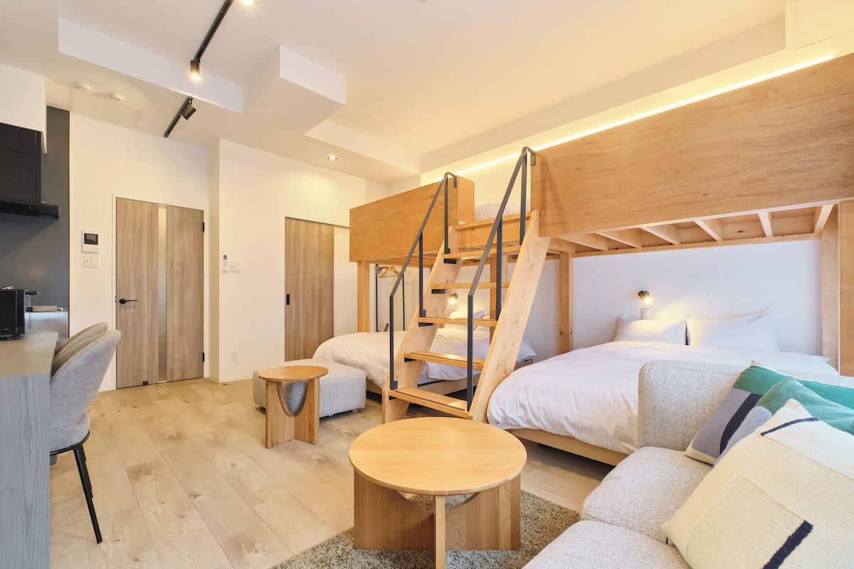 A modern bedroom with a bunk bed, a desk, and a sofa.