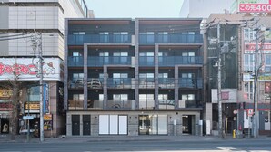A multi-story building with a modern architectural design, featuring a ground floor with large glass windows and a visible entrance.