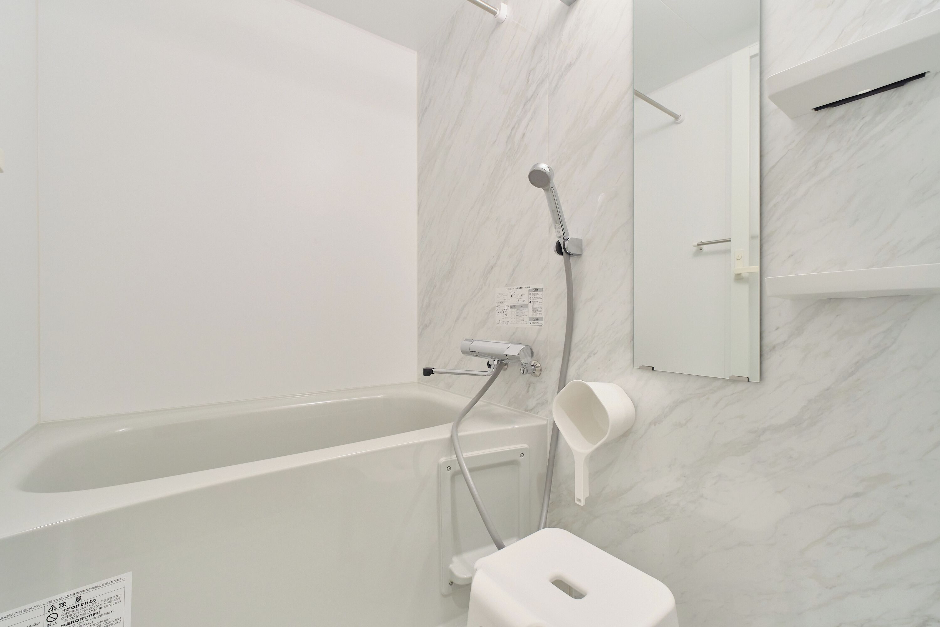 A bathroom with a bathtub, a shower, a toilet, and a marble wall.