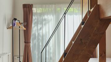 A staircase with wooden railings, a curtain, and a clothing rack with hangers and a bottle.