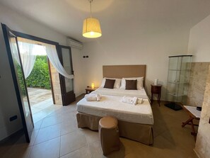 A bedroom with a bed, a bedside table, a lamp, a bench, and a glass cabinet.