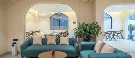 A modern living room with teal sofas, a wooden coffee table, and a potted plant.