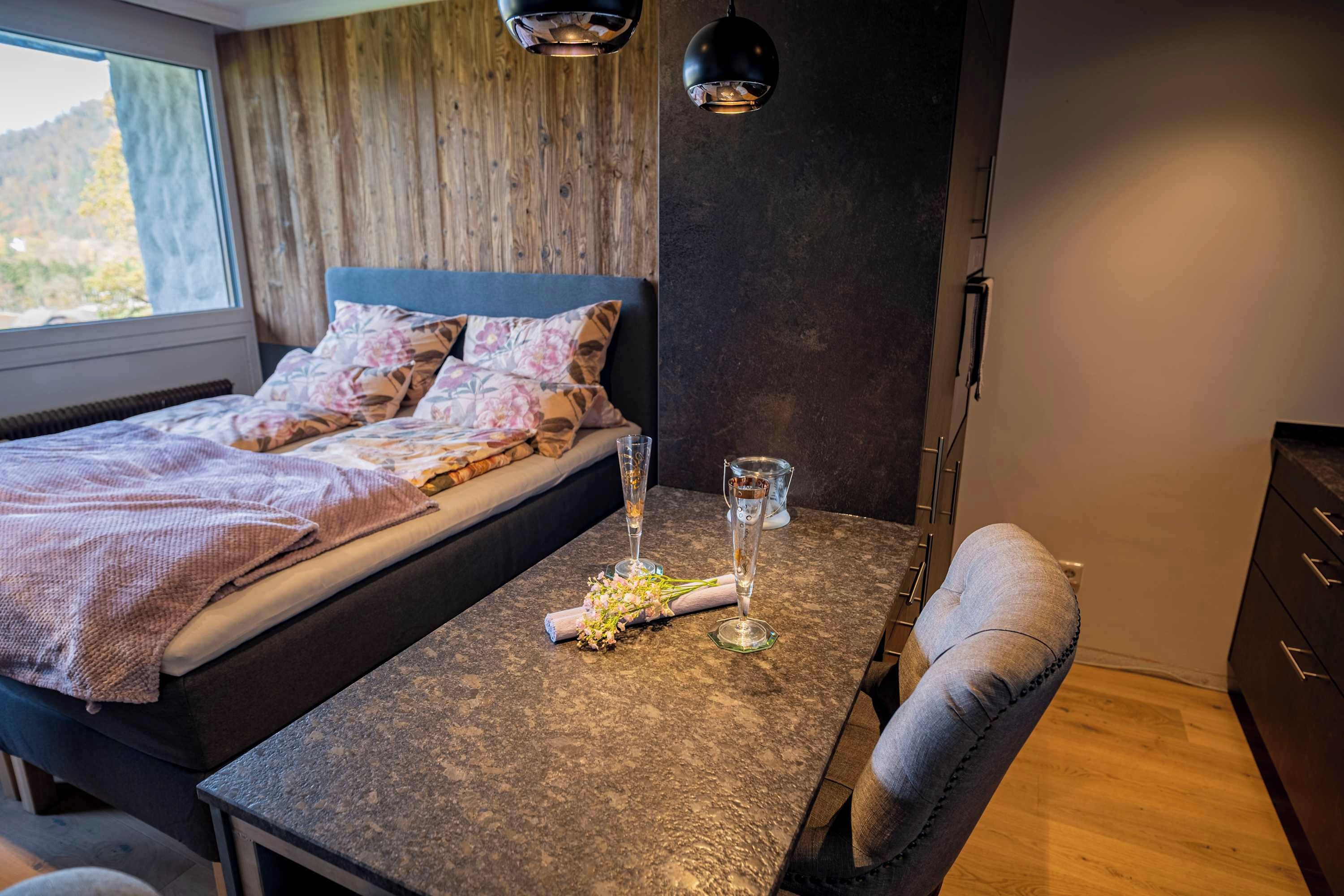 Et soveværelse med en seng, et bord med et glas vand og en stol.