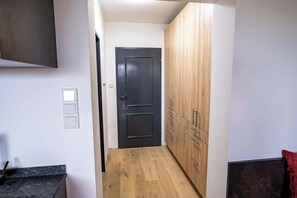 Ein Flur mit einer dunklen Tür, Holzsäcken und einem Lichtschalter an der Wand.