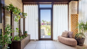 Una habitación con puerta de vidrio corrediza, un sofá y plantas en macetas.