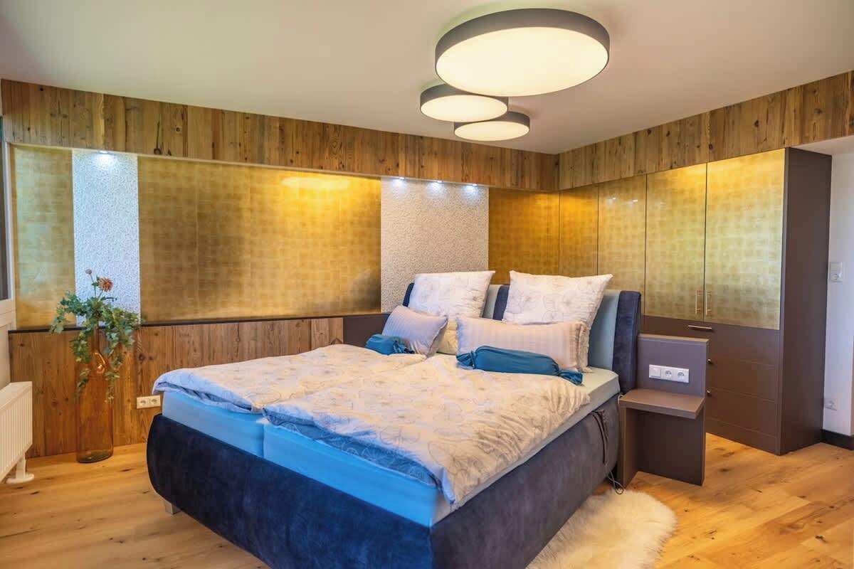 Un dormitorio con cama, mesitas de noche, un espejo y paneles de madera.