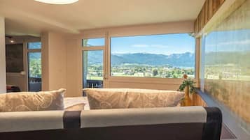 Une chambre avec une grande fenêtre, un lit et une vue sur un paysage montagneux.