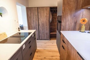 A modern kitchen with a wooden cabinet, a white countertop, and a flower vase. - Premium Lake view Suite | Adults only (Strobl)