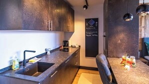 Una cocina moderna con armarios oscuros, un fregadero y una zona de comedor con una mesa dispuesta para dos personas.