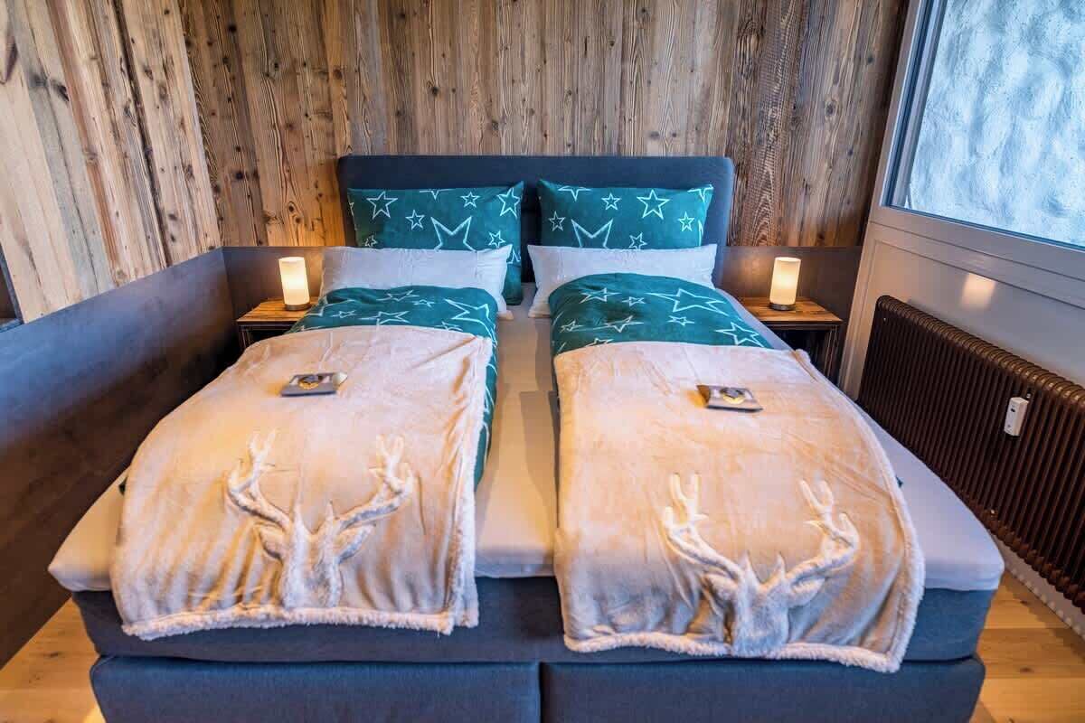 En dobbeltseng med to puder, et natbord med lampe og et vindue med udsigt.