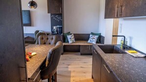 Una cocina moderna con cafetera integrada, zona de comedor con banco y un mueble grande.