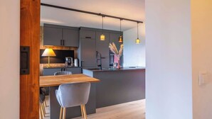 Una cocina moderna con una mesa de comedor de madera, armarios grises, luces colgantes y una pequeña isla.