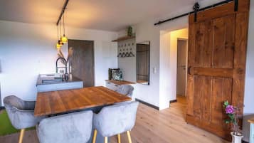 Une cuisine moderne avec une table et des chaises en bois, un luminaire suspendu et une porte coulissante de style rustique.