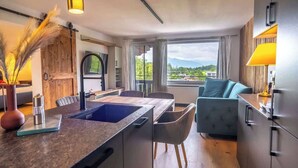 Una cocina moderna con una isla central, un área de comedor con sofá y vistas al exterior.
