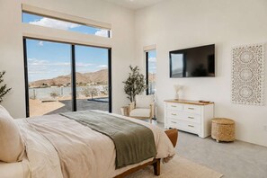 Ein Schlafzimmer mit einem Bett, einem Fernseher, einer Kommode und Blick auf die Wüste.