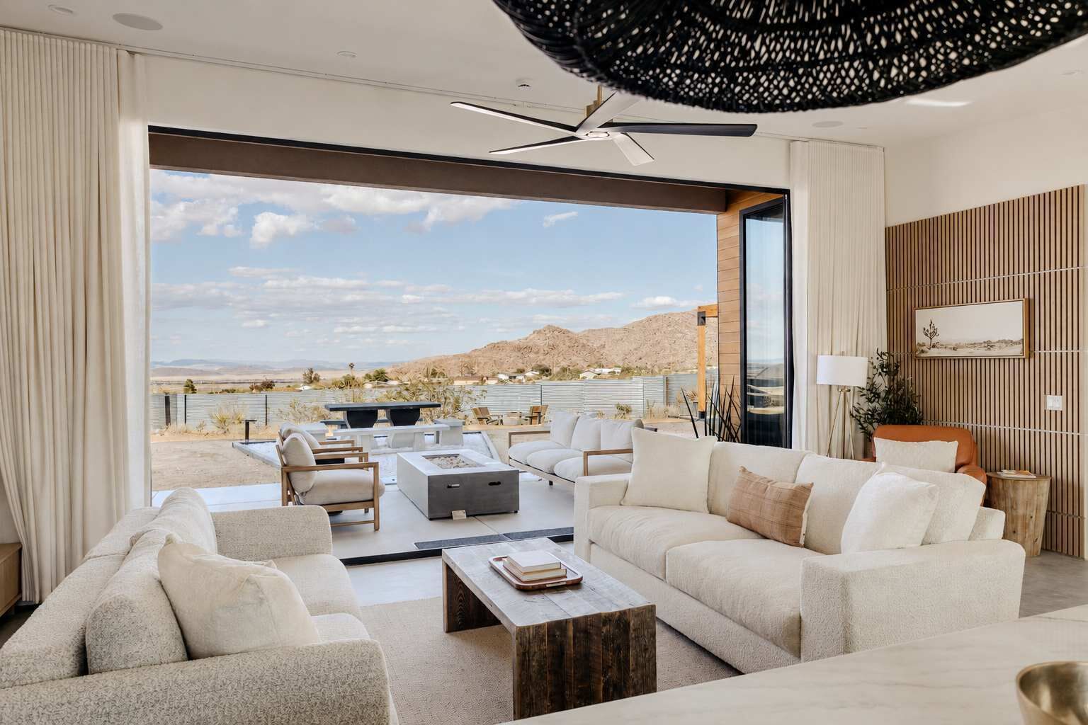 Un salon moderne doté d’une grande fenêtre, d’un ventilateur de plafond et offrant une vue sur un paysage désertique.