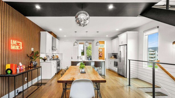 A modern kitchen with a wooden accent wall, a disco ball, and a neon sign. - Sleeps 24 | Sauna, Peloton, Balcony + Fire pit (Nashville)