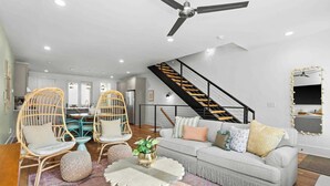 A modern living room with a sofa, chairs, a coffee table, and a staircase. - Sleeps 24 | Sauna, Peloton, Balcony + Fire pit (Nashville)