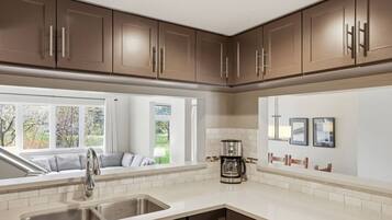 A kitchen with a sink, a coffee maker, and a view of the outdoors.