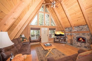 Ein gemütliches Loft mit Kamin aus Stein, Holzbalken, einer Ledersofa und einem Fernseher.