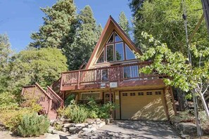 Eine Holzhütte mit Balkon, Garage und einem Steinweg, der zum Eingang führt.