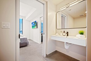 A modern bathroom with a large mirror, white sink, and a towel rack. - 501 FIRST LUXURY 1BR+DEN (Miami)