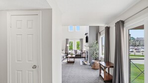 Un salon spacieux avec une grande fenêtre, un canapé, une table basse et une plante.
