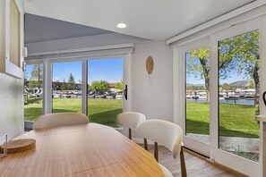 A dining area with a wooden table and chairs, large windows with a view of a park and boats. - Modern Studio Condo with Private Boat Dock (South Lake Tahoe)