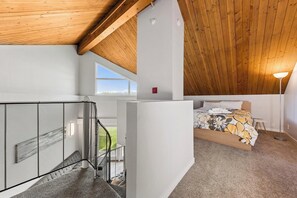 A bedroom with a bed, a window, a balcony with a railing, and a ceiling with wooden beams. - Modern Studio Condo with Private Boat Dock (South Lake Tahoe)