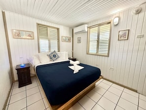 Een slaapkamer met een bed, nachtkastje en een luchtbevochtiger aan de muur.