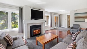 A living room with a fireplace, a flat-screen TV, and a sofa with striped pillows.