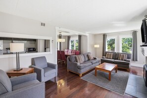 Una sala de estar moderna con un sofá, sillones, una mesa de centro y un televisor.