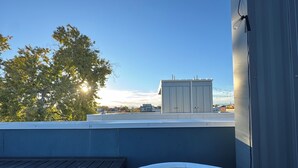 Tagterrasse med jacuzzi, træterrasse og udsigt til byens skyline.