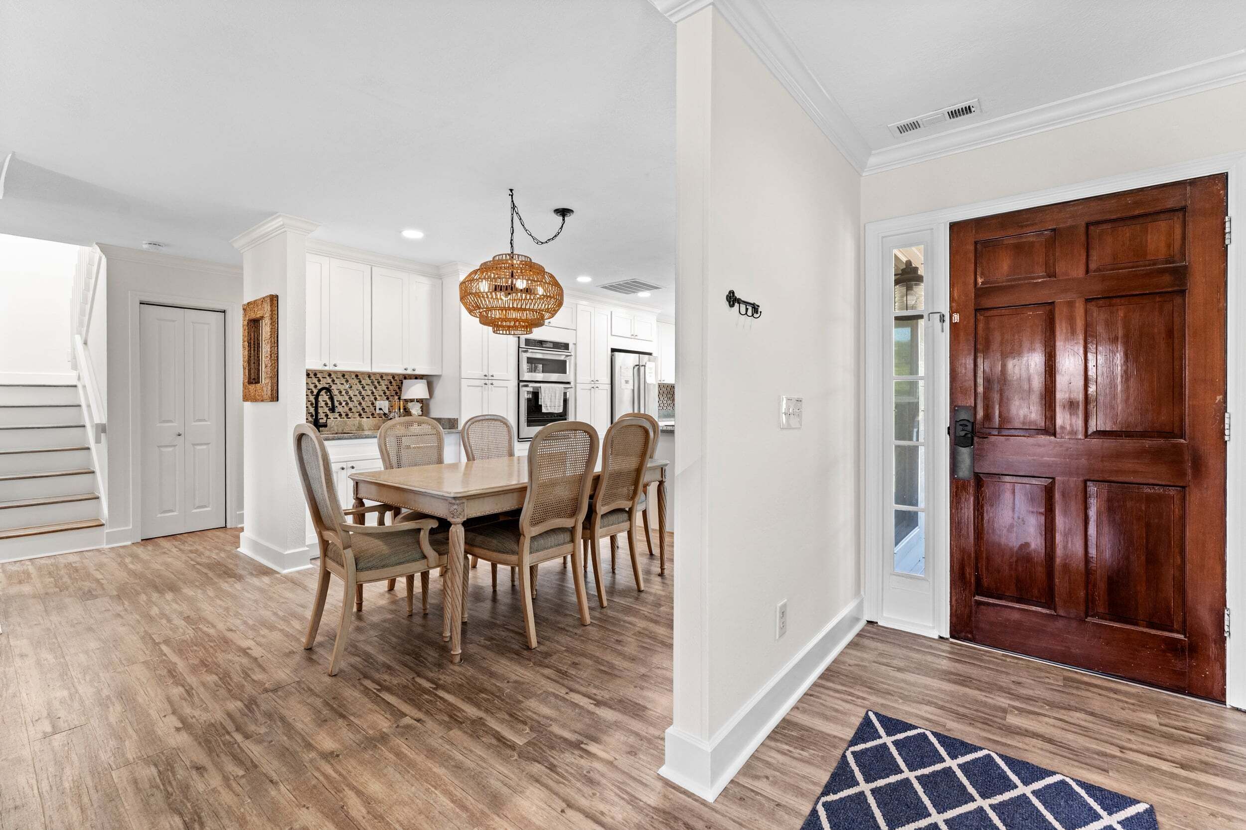 A dining area with a wooden table and chairs, a chandelier, and a wooden door.
