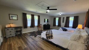 Une chambre avec deux lits, un bureau, une chaise, un ventilateur de plafond et une vue sur l’extérieur.