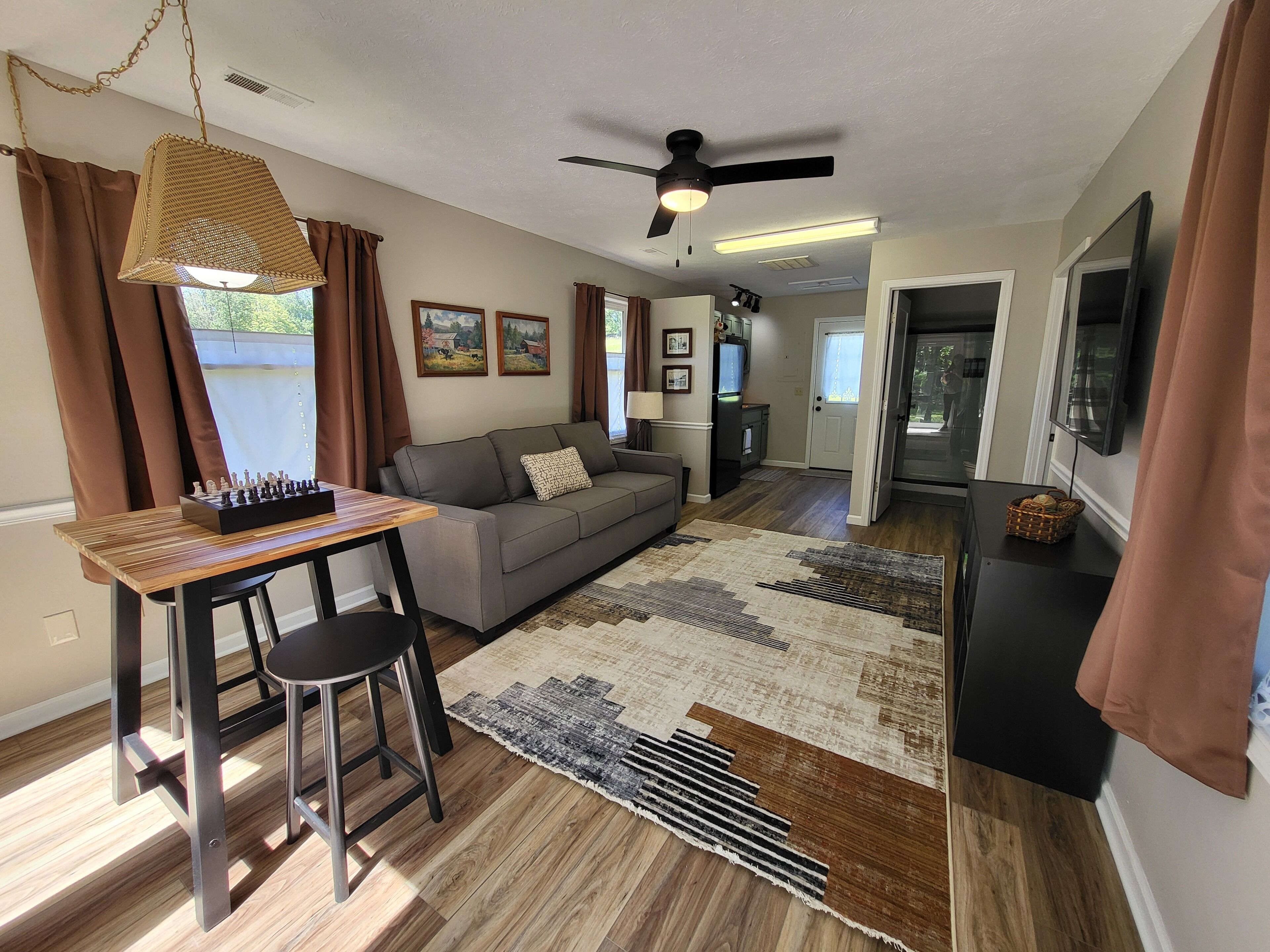 A living room with a sofa, a coffee table, a TV, and a ceiling fan.