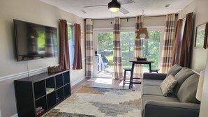 Un salon équipé d’un téléviseur à écran plat, d’un canapé, d’une table basse et d’un tapis à motifs.