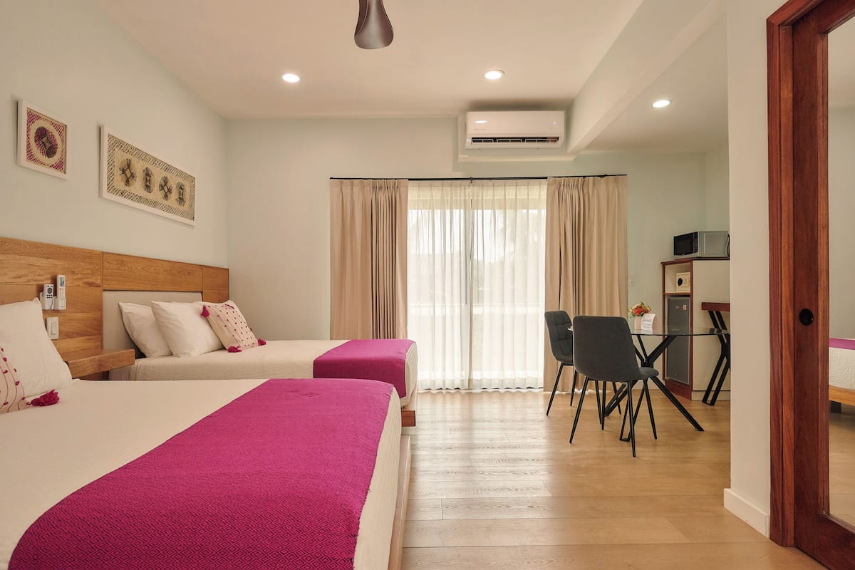 Habitación de hotel con dos camas, un escritorio y una silla.