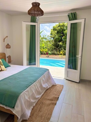 A bedroom with a bed, a hanging lamp, and a view of a swimming pool. - Casa Helena – Brand-New Villa – Private Pool &Tropical Garden – 6 P – Martinique (Saint-Esprit)