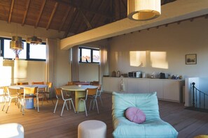 Un grand espace de vie comprenant une table à manger, des chaises, un canapé avec un coussin et un coin cuisine équipé d’un four à micro-ondes et de placards.