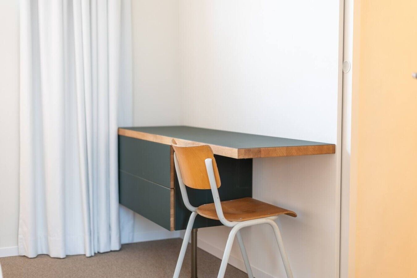 A corner desk with a chair, a door, and a curtain.