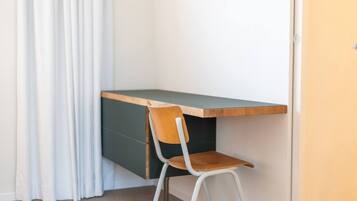 A corner desk with a chair, a door, and a curtain.