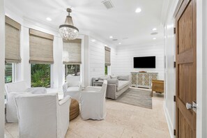 A spacious living area with a sofa, chairs, a television, and a wooden door.