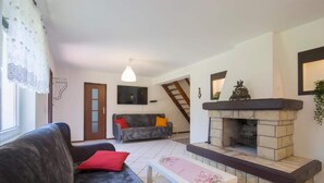Sala de estar com lareira, sofá, mesa de centro e escada para outro andar.